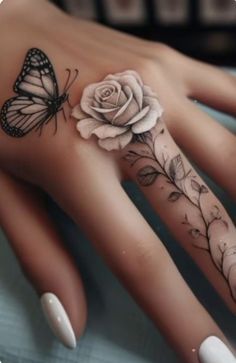 a woman's hand with a butterfly and rose tattoo on it