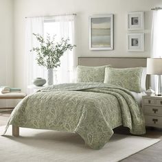 a bed in a bedroom with a green comforter and pillows on top of it