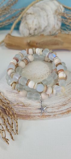 two bracelets with beads and a cross on them sitting on top of a table