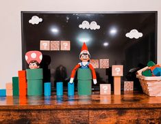 an elf is standing in front of some blocks and toys on a table with a black background