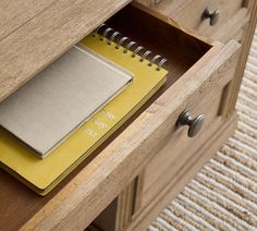 an open drawer with a notepad and notebook in it, on carpeted area