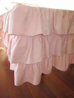 pink ruffled bedspread on wooden floor in room