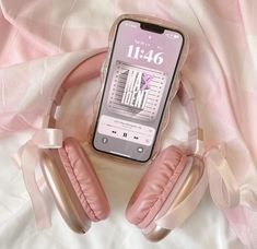 an iphone with headphones on top of it sitting on a pink and white blanket