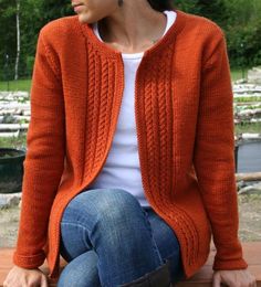 a woman in an orange cardigan sitting on a bench