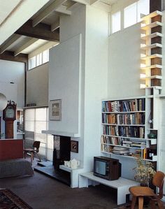 a living room filled with furniture and bookshelves next to a fire place under a window