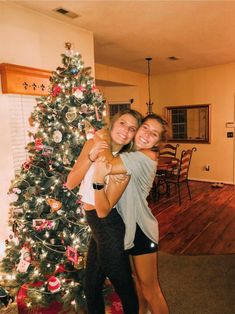 two women hugging each other in front of a christmas tree