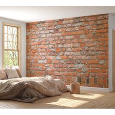 a bed sitting in front of a brick wall next to a window with sunlight streaming through it