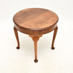 a small wooden table with two legs and a round top on one end, against a white background