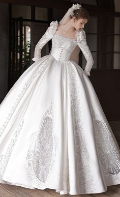 a woman in a white wedding dress standing on a wooden floor