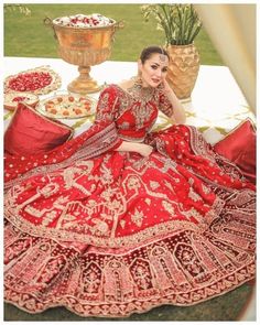 a woman sitting on top of a table wearing a red and gold wedding dress,