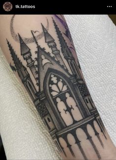 a black and white tattoo on the arm of a person with a clock tower in the background