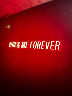 you & me forever neon sign on the side of a wall in a dark room