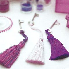 two pairs of tasseled earrings sitting next to each other on a white table