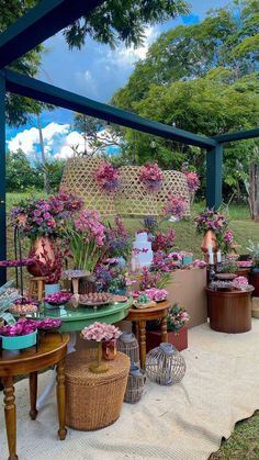 an outdoor area with flowers and plants on the table, in front of a gazebo