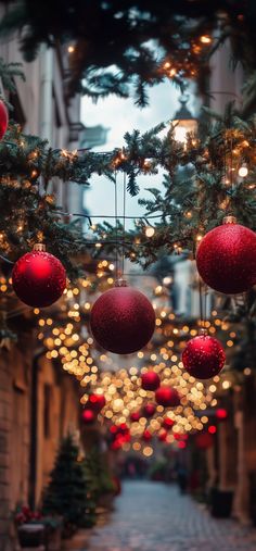 an alley with christmas decorations hanging from it's ceiling and lights on either side