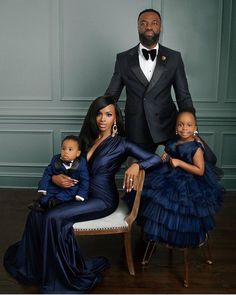 a man in a tuxedo poses with his two daughters and their baby son