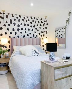 a bedroom decorated in black and white with polka dots on the wall behind the bed