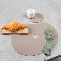 a croissant sitting on top of a table next to a cup and plate