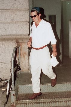 a man in white is walking down the stairs with his hat on and sunglasses on