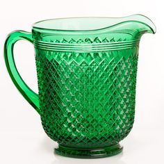 a green glass pitcher sitting on top of a table