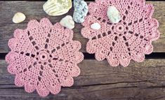 two crocheted doily on a wooden table with shells and seashells