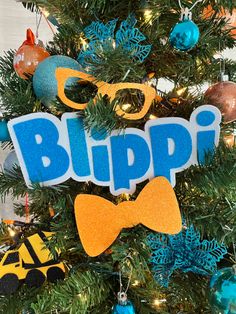 a christmas tree decorated with blue and orange decorations, including an ornament that says blipp