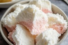 a bowl filled with white and pink desserts on top of a table next to another bowl