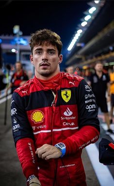 a man in a red and black racing suit is posing for the camera with his hands on his hips