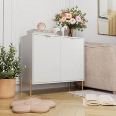 a white cabinet sitting on top of a hard wood floor next to a beige couch