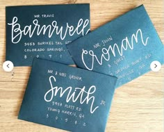 three blue business cards with white writing on them sitting on a wooden table next to each other