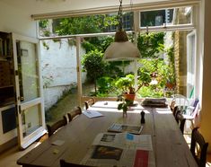 a wooden table sitting in front of a window filled with books and magazines on top of it