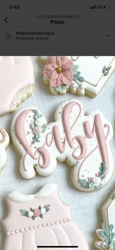 some cookies that are on top of a white table with pink and blue decorations in the shape of baby's name