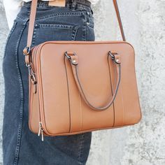 a woman holding a brown purse in her hand