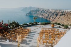 an outdoor ceremony set up with wooden chairs and tables overlooking the ocean in front of cliffs