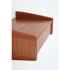 a close up of a wooden shelf against a white wall