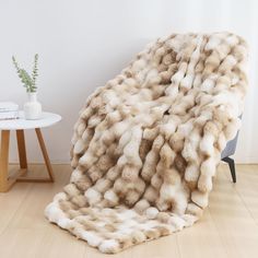 a white and brown fur blanket sitting on top of a wooden floor next to a table