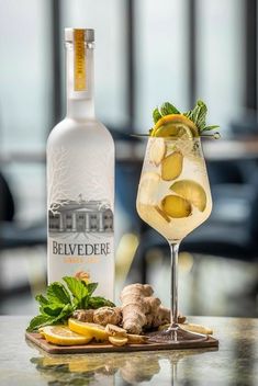 a glass filled with ice and lemons next to a bottle of belvedere