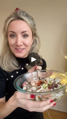 a woman holding a glass bowl filled with food