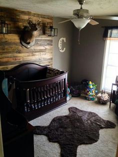 a baby's room with a crib and deer head on the wall