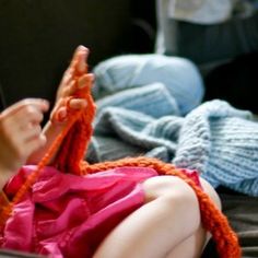 a woman is laying down on the floor with her hands in her pockets and knitting