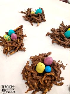 chocolate bird's nests with colored eggs on them sitting on a white plate