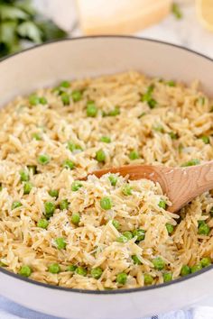 a pot filled with rice and peas on top of a blue towel next to a wooden spoon