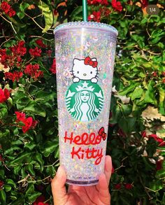 a hand holding up a starbucks cup with hello kitty on the lid and glitters