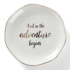 a white and gold plate with the words and so the adventure begins written on it