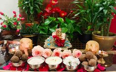 a table topped with lots of different types of desserts and flowers next to potted plants