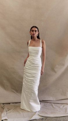 a woman standing in front of a white backdrop wearing a dress with ruffles