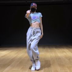 a woman standing on top of a wooden floor in front of a black wall and wearing headphones