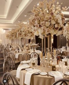 the tables are set with white and beige flowers in tall vases on each table