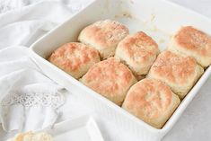 a white dish filled with biscuits on top of a table