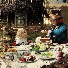 two children sitting at a table with cakes and desserts